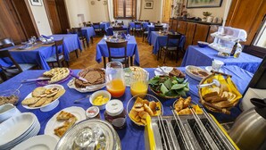 A dining area with multiple tables set for breakfast, featuring a variety of food items and beverages. - Villa Moorings (Barga)