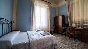 A bedroom with a bed, a desk, a chair, and a wardrobe.