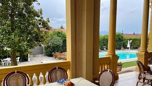 A dining area with a table set for two, overlooking a swimming pool and a garden. - Villa Moorings (Barga)