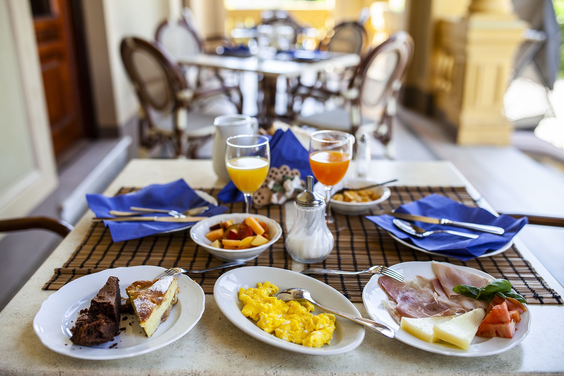 Desayuno con platos de comida, un salero y vasos de jugo de naranja.