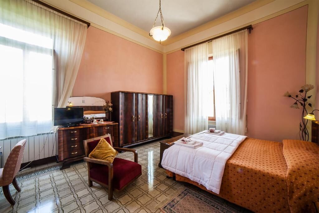 Quarto de hotel com cama, televisão, guarda-roupa, secretária e uma cadeira.