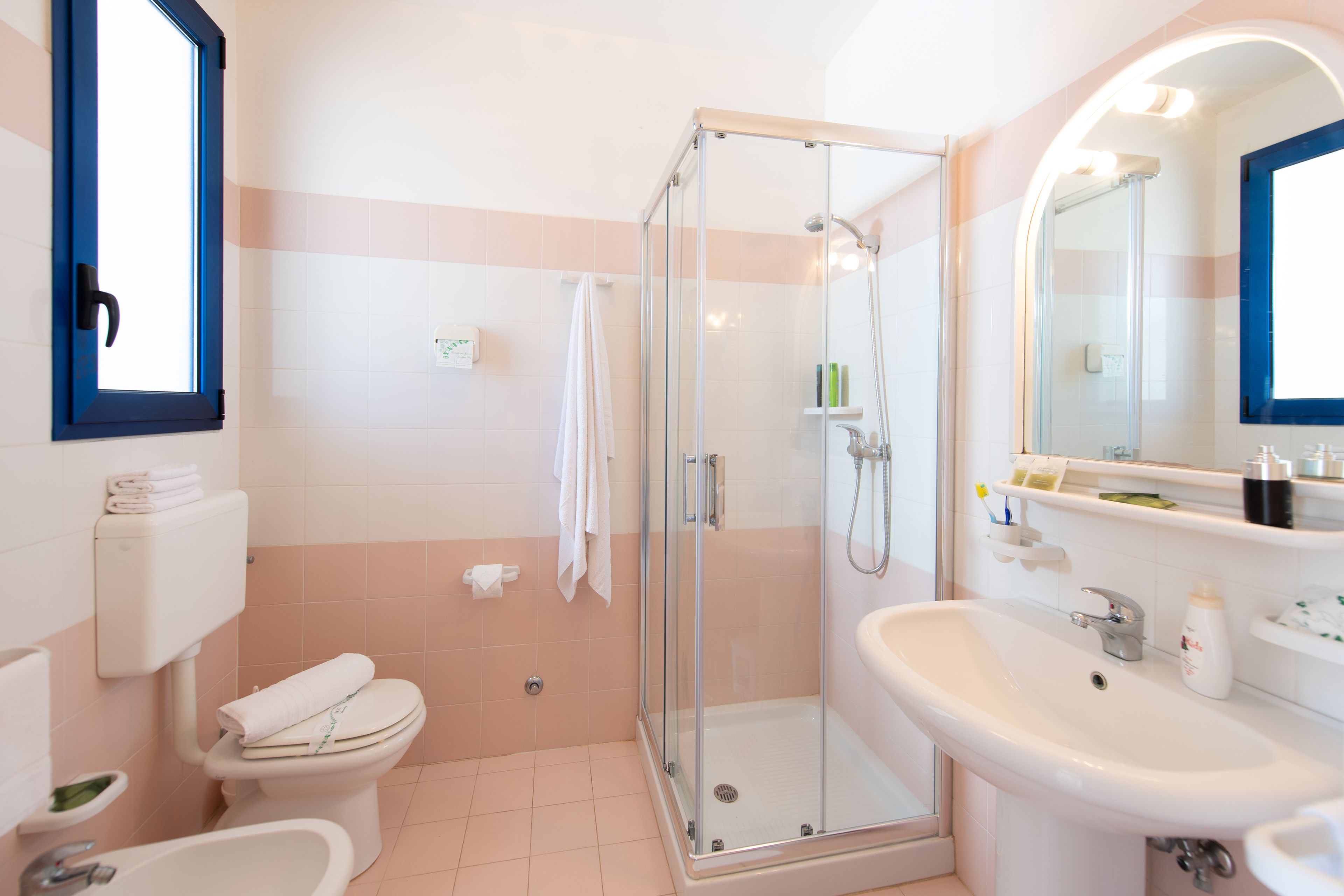 Un baño moderno con ducha de vidrio, lavamanos blanco y retrete.