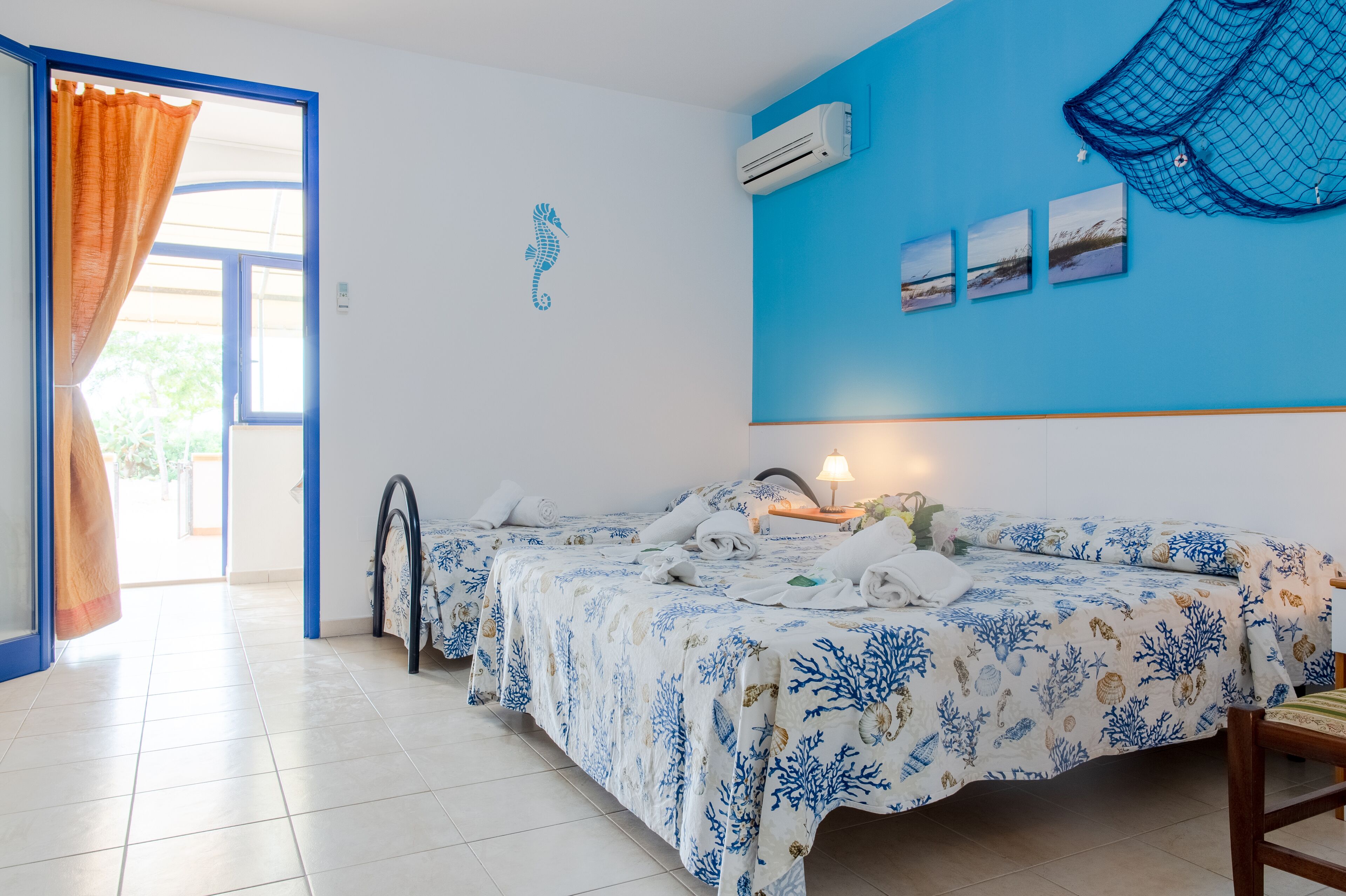 A hotel room with two beds, a blue wall, and a seahorse decal.