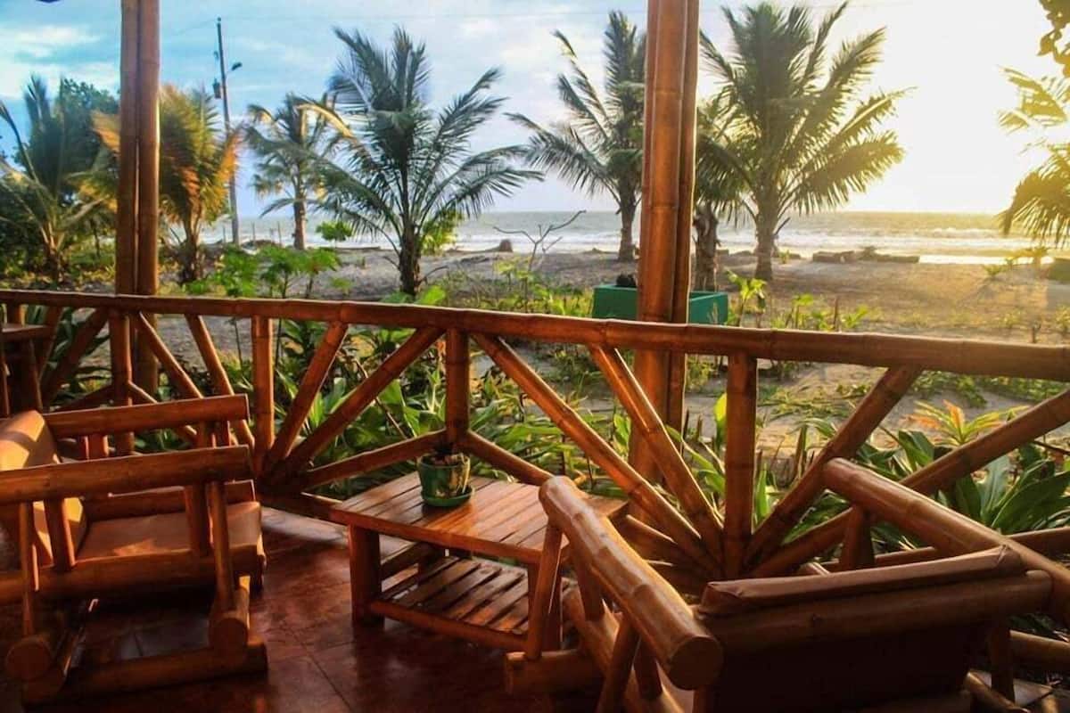 Eine Holzterrasse mit Blick auf den Strand und Palmen.
