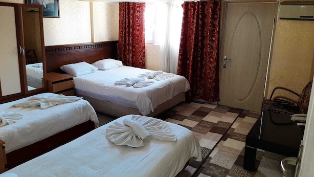 A hotel room with two beds, a wooden headboard, a mirror, a wardrobe, and a checkered floor. - Florin Hotel (Istanbul)
