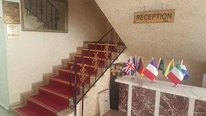 A reception area with a marble counter, red carpeted stairs, and multiple flags. - Florin Hotel (Istanbul)