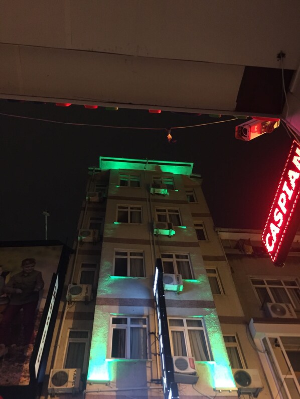 Un edificio de varios pisos, con unidades de aire acondicionado y un letrero de neón que dice "CASPIAN".