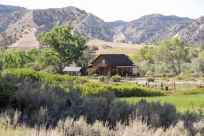 A rustic log cabin with a large porch, surrounded by lush greenery and mountains in the background. - Cozy Henrieville Cabin: 18 Mi to Bryce Canyon NP! (Henrieville)