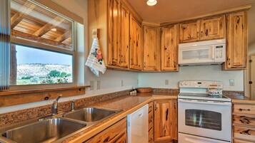 A kitchen with wooden cabinets, a stainless steel sink, a built-in microwave, and a dishwasher.
