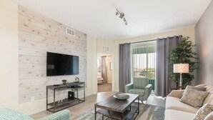 Sala de estar con televisor, sofá, sillón y una mesita.