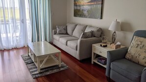 Ein Wohnzimmer mit einer Couch, einem Couchtisch, einem Beistelltisch mit Lampe und einem Gemälde an der Wand.