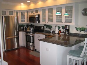 A kitchen with stainless steel appliances, white cabinets, and a granite countertop. - Experience Ocean City like never before at Sea Grass #5! (Ocean City)
