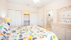 Quarto com cama, penteadeira, espelho e ventoinha no teto.