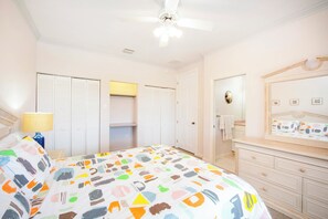 Un dormitorio con cama, cómoda, espejo y ventilador de techo.