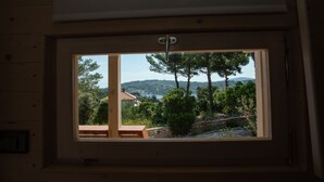 A window with a view of a landscape including trees, a house, and hills.