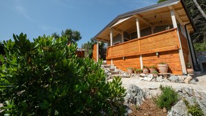A modern wooden house with a balcony and potted plants.