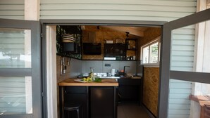 A compact kitchen with wooden cabinetry, a central island with stools, and a view through an open door.