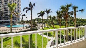 A hotel with a pool, palm trees, and a clear blue sky. - Beachfront 2BR/2BA condo with pool, wifi, and Marco Island views. (Marco Island)