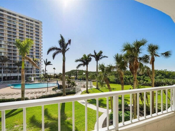 A hotel with a pool, palm trees, and a clear blue sky. - Beachfront 2BR/2BA condo with pool, wifi, and Marco Island views. (Marco Island)