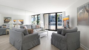 A modern living room with grey sofas, a white coffee table, and artwork on the walls. - Beachfront 2BR/2BA condo with pool, wifi, and Marco Island views. (Marco Island)