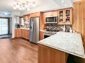 A modern kitchen with wooden cabinets, stainless steel appliances, and a granite countertop.