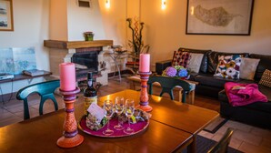 Un salon chaleureux avec une table en bois dressée pour un repas, une cheminée et un canapé confortable.