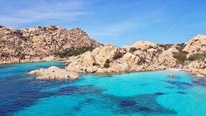 A coastal landscape with rocky terrain and clear turquoise waters.