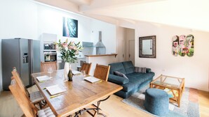 A modern kitchen with a dining area, a sofa, and a small table. - Large luxury apartment near the ocean with terrace between sea, golf course and lake  (Seignosse)