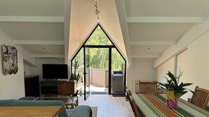 A modern living room with a TV, sofa, dining table, and a view through a large window. - Large luxury apartment near the ocean with terrace between sea, golf course and lake  (Seignosse)
