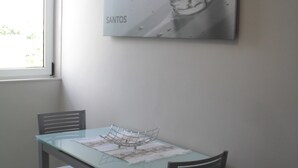 A dining area with a glass-top table, four chairs, and a wall-mounted picture frame.