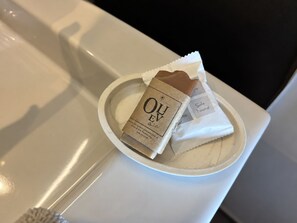 A white plate with a bar of soap and a tissue on a white countertop.