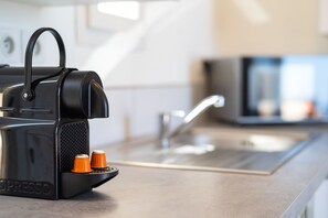 Une cuisine équipée d’une machine à expresso noire, d’un évier et d’un plan de travail.