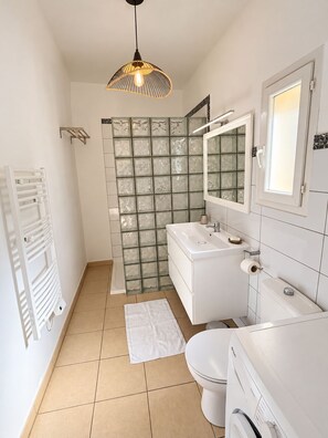 Een moderne badkamer met een wit wastafelmeubel, toilet en douchegedeelte.