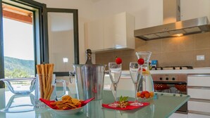 A modern kitchen with a glass table displaying snacks, a cocktail shaker, and glasses. - Refined independent villa for design lovers in the beautiful Chia bay (Domus De Maria - Chia)