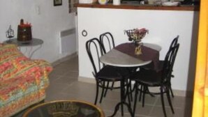 Un espace de vie compact comprenant un coin repas, une cuisine et un petit coin salon.