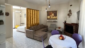 Un salon moderne avec un canapé d ’angle, une table à manger entourée de chaises violettes, une cheminée et un tableau accroché au mur.