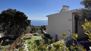 Un bâtiment blanc surmonté d’une antenne parabolique, entouré de verdure et sous un ciel dégagé.