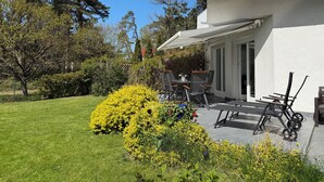 Una casa con un patio, una mesa con sillas y un pequeño jardín con flores amarillas.
