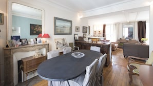 Een ruime woonkamer met een grote eettafel, comfortabele zithoek en een open haard.