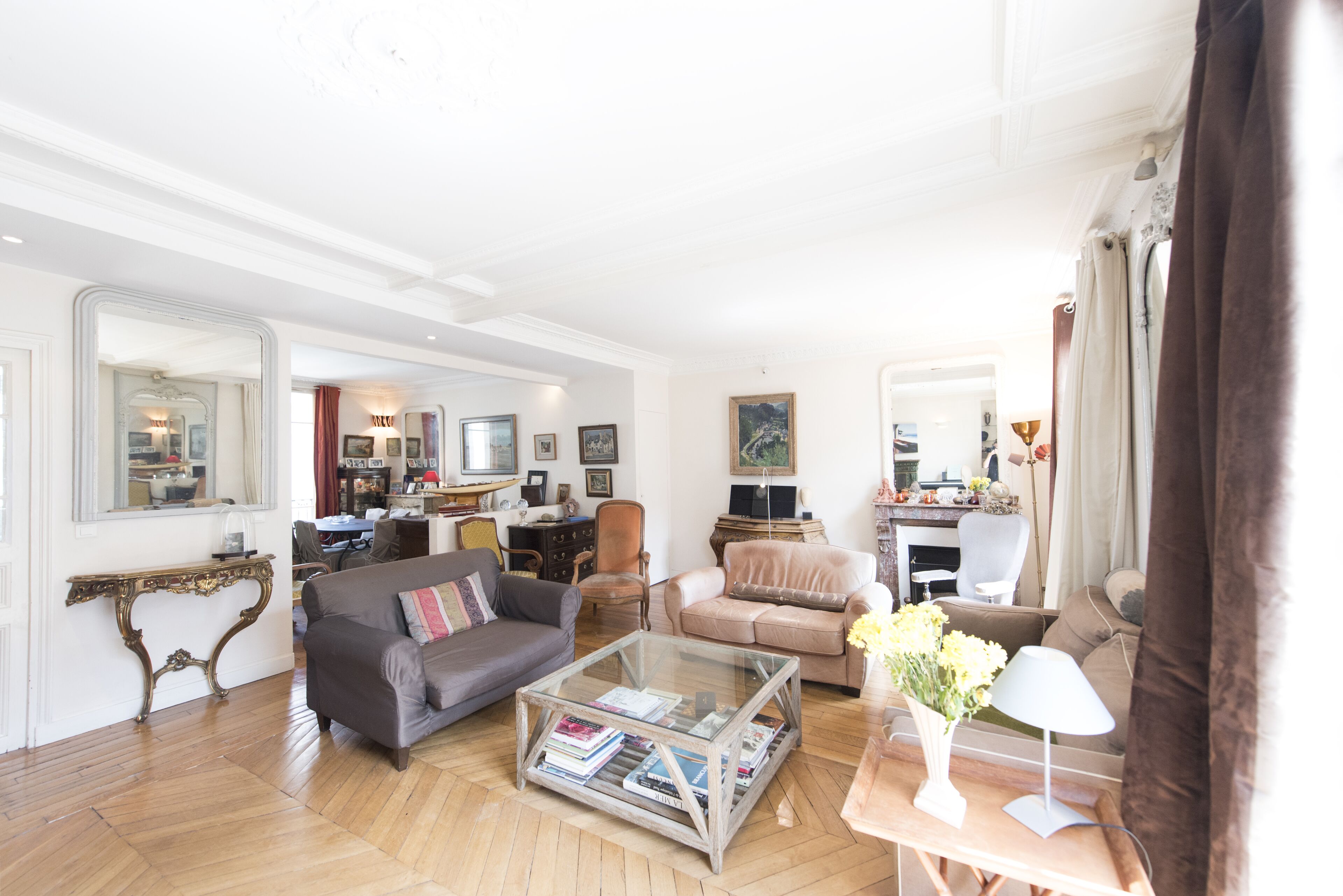 Ein großzügiges Wohnzimmer mit Sofa, Sesseln und Couchtisch. Im Hintergrund befindet sich ein Essbereich mit Tisch und Stühlen.
