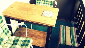 Uma pequena mesa de madeira com um descanso de lugar, rodeada por duas cadeiras com estofamento verde e branco xadrez.
