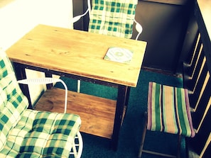 Relax in a charming seating area with a wooden table and two comfortable chairs, one with a striped cushion.