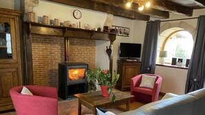 A cozy living room with a brick fireplace, red and grey furniture, and a television. - Character cottage "les vieux chênes" very quiet near ROCAMADOUR and Gramat  (Théminettes)