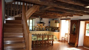 A wooden staircase leading to a dining area with a tiled floor, wooden chairs, and a table with a floral tablecloth. - Character cottage "les vieux chênes" very quiet near ROCAMADOUR and Gramat  (Théminettes)