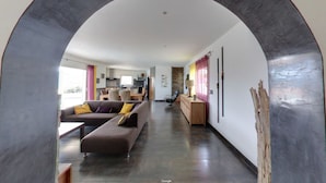 A modern living room with a sofa, a dining area, and a kitchen in the background. - Contemporary villa, with clim-160 m2, swimming pool, 5 mn from beaches & shops (Monticello)