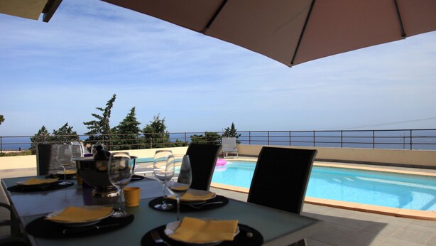 A dining table set for two with a view of the pool and ocean. - Contemporary villa, with clim-160 m2, swimming pool, 5 mn from beaches & shops (Monticello)