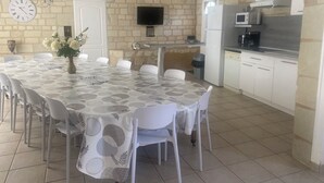 A compact kitchen with a dining area, featuring a stone wall, a flat-screen TV, and modern appliances. - In the heart of Fontevraud-l'Abbaye (Fontevraud-L'abbaye)