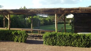 A rustic outdoor seating area with wooden benches and a thatched roof structure. - In the heart of Fontevraud-l'Abbaye (Fontevraud-L'abbaye)