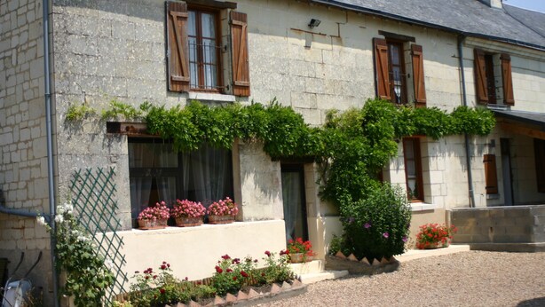 A stone building with wooden shutters, a gravel driveway, and potted plants. - In the heart of Fontevraud-l'Abbaye (Fontevraud-L'abbaye)