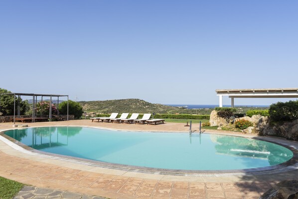 Une piscine avec des chaises longues et vue sur la mer.